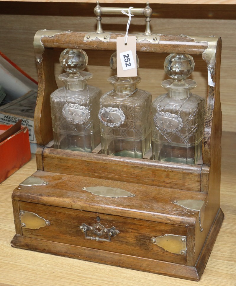An oak and brass tantalus, with three decanters